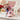 Valentine's Day Play Ball Red Sox Gift, a pink Red Sox cap filled with Godiva chocolates, Cracker Jack, Coca-Cola, baseball chocolates and candy hearts, on a coffee table with roses