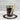 Jar of layered cupcake dessert with a wooden spoon and decorative string on a marble surface.
