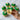 Hand holding a cupcake with green frosting and Easter decorations, surrounded by more cupcakes on a marble surface.