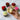 Hand holding a cupcake with floral decorations in front of other cupcakes on a marble surface