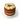 Three-layered cake with cream and chocolate chips on a clear stand against a white background