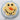 Snowman-shaped cake with yellow frosting, black buttons, and an orange carrot on a marble background
